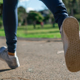 Close-up of a person running along a gravel path alongside some trees and grass