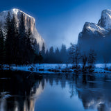 Snowy mountains behind a lake and winter trees with a rich blue sky