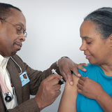 A picture of a doctor injecting the flu jab into the arm of a woman
