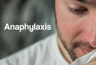 A close up of a man blowing his nose. The word – Anaphylaxis – can be seen