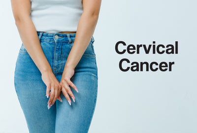 The waist and lower half of a woman. She is wearing jeans and a white t-shirt. Her hands are in front of the zip and button part of the jeans. The words – Cervical Cancer – can be seen