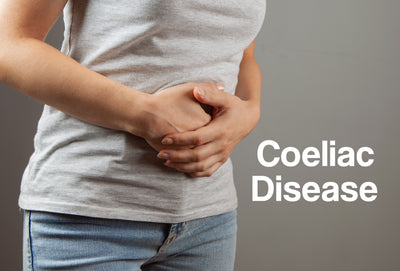 A woman with both her hands on her stomach, as though in pain. The words – Coeliac Disease – can be seen