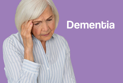 An elderly woman in a striped shirt – she is looking towards the ground and has one hand rubbing her forehead – she looks confused. The word – Dementia – can be seen