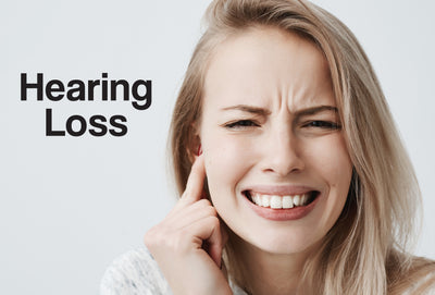 A woman has a finger pointing to her right ear – she look as though she is struggling to hear what is going on. The words – Hearing Loss – can be seen