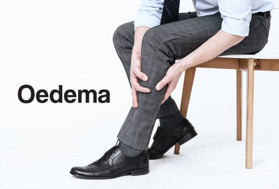 The bottom half of a man sitting on a chair. The man is gripping his leg, as though in pain. The word – Oedema – can be seen
