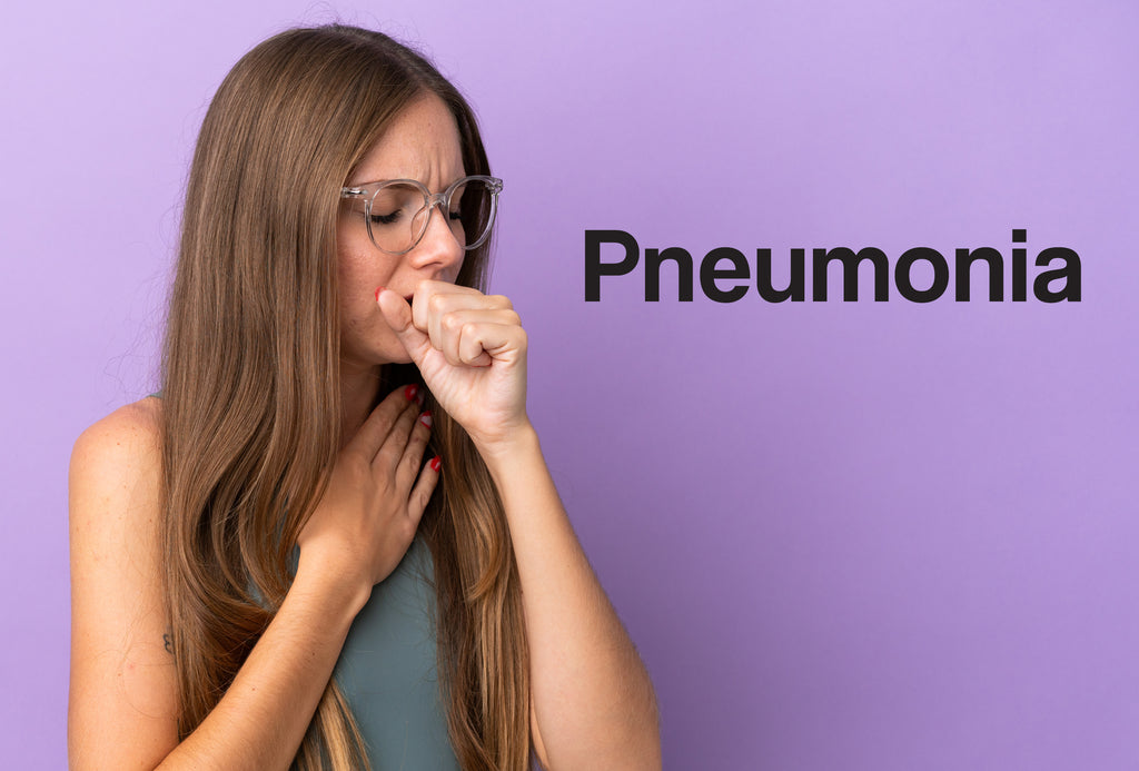 A young woman has an arm against her chest and a hand against her mouth, although she's coughing and is in pain. The word – Pneumonia – can be seen