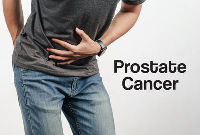 A man in old jeans and a dark grey t-shirt is leaning forward. One of his hands is on his rear, his other hand is on his stomach – the pose infers that the man is in pain. The words – Prostate Cancer – can be seen