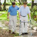A man using a Zimmer frame on a path. He is being helped by a male friend
