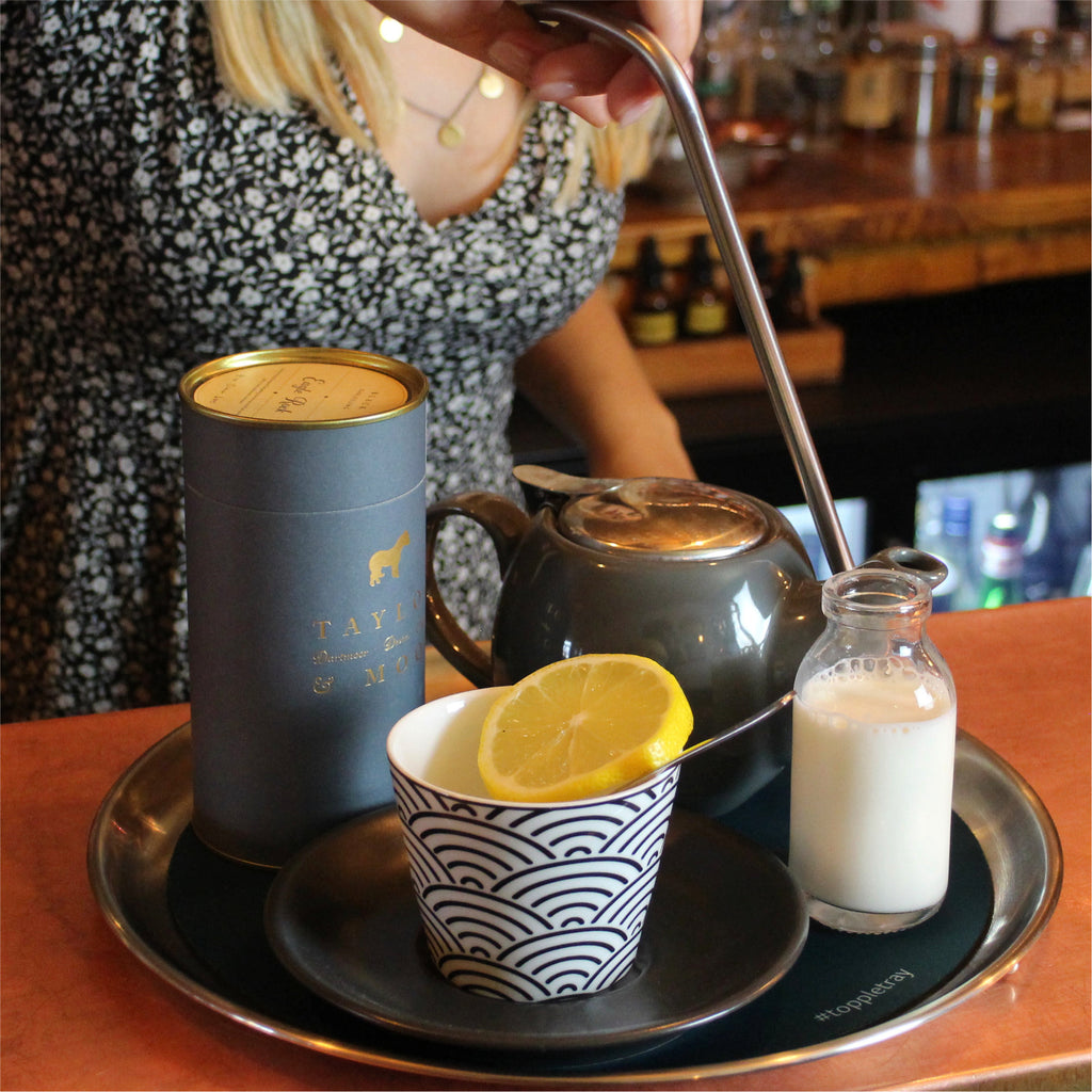 Single handed topple tray with teapot, teacup and milk