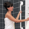 shows a woman wrapped in a towel, using a Mobeli Grab Handle in a shower cubicle