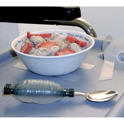 The elastack tape wrapped around a dessert spoon next to a bowl of what appears to be mini shredded wheat and sliced strawberries