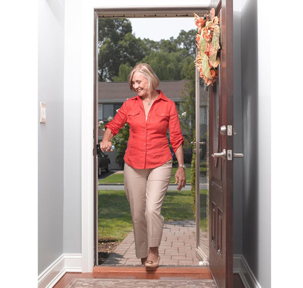 shows a woman moving through a front-door with a step, using the Flip-A-Grip Support Handle