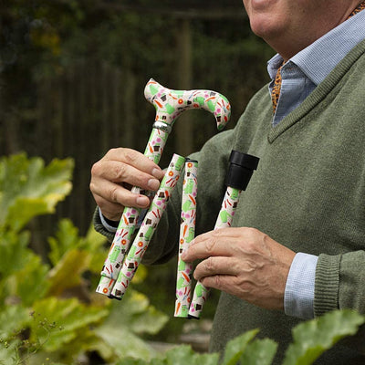 the image shows a man in the garden holding the classic canes folding fashion derby cane with a garden design