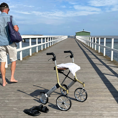 A Let's Go Out Rollator on a promenade on a sunny day.