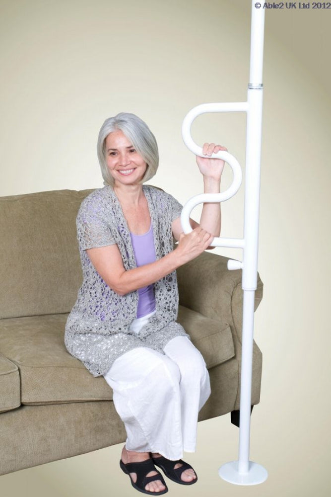 shows a woman with grey hair sitting on a fabric couch and holding on to the white security pole