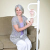 shows a woman with grey hair sitting on a fabric couch and holding on to the white security pole