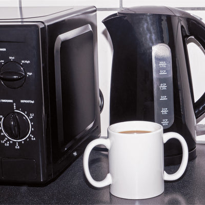 Two handled mug pictured next to a kettle and a microwave