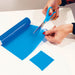 shows someone cutting a bit of a blue non slip silicone roll