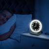Wake n shake alarm clock on bedside cabinet whilst man sleeps 
