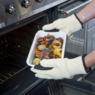 shows someone wearing the anti burn gloves to remove an oven dish of roasted vegetables from an oven