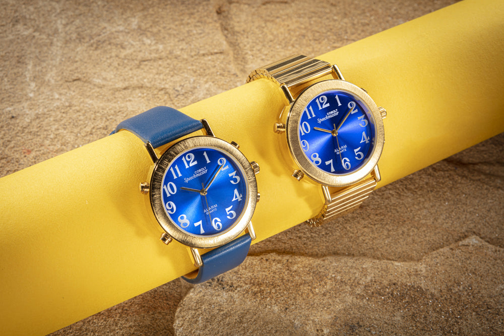 the two versions of the gold and blue analog talking watches, one with a leather strap and one with an expanding strap