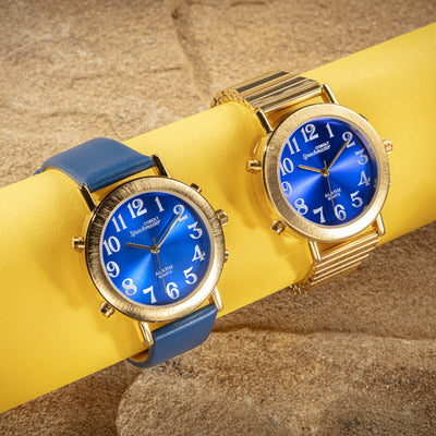 the two versions of the gold and blue analog talking watches, one with a leather strap and one with an expanding strap