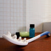 The image shows an Etac Long Handled Hair Washer placed on a bathroom shelf