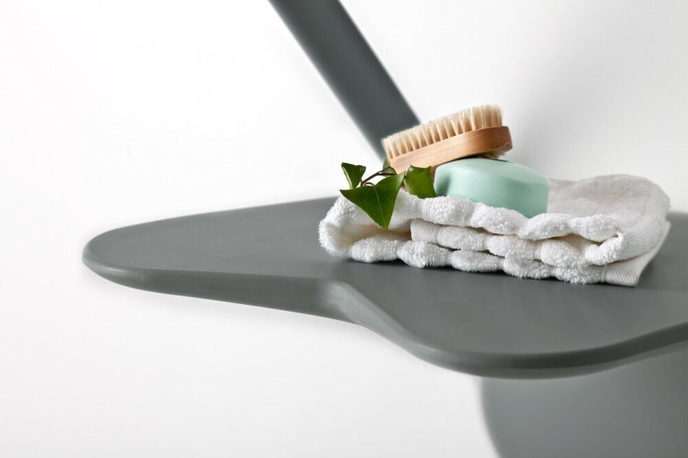 Close up of grey Shower seat with flannel, soap and brush on it