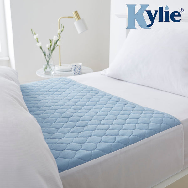 The image shows the pale blue Kylie Bed Pad in place on a bed