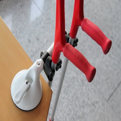 The image shows the mobeli dual cane holder attached to a table edge and holding two crutches
