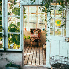 An old type of greenhouse. Inside are plants and an old comfy chair