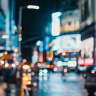 A very blurry photo of a busy city scene with large posters in the background along with several cars