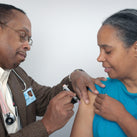 A picture of a doctor injecting the flu jab into the arm of a woman