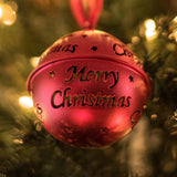 A close up on a Christmas bauble hanging on a Christmas tree. The bauble has the words – Merry Christmas – on it