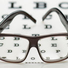 A pair of glasses resting on an out of focus eye chart