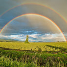 Two rainbows are shown above some green fields
