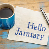 A coffee cup with a piece of paper next to it with the words Hello Janaury on it