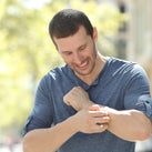A picture of a man scratching his left arm