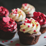 Six chocolate cupcakes on a plate. Three are topped with red icing and three are topped with white icing