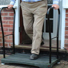A man coming out of his front door and stepping onto the Bigfoot Half Step which has two handles in place