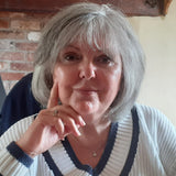 A close-up of Lesley's face – her right hand is raised to her face, in a 