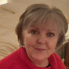 A close up of Lesley, who is wearing a red top and looking towards the camera
