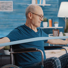 An image of a man in a wheelchair using a stretch band to exercise with