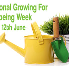 A yellow watering can on a white background is in front of a white pot containing a grassy-looking plant. There is a small green spade leaning against the watering can. The words – National Growing For Wellbeing Week, 6th-12th June – can also be seen