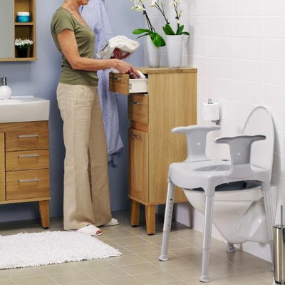 Woman in bathroom with toilet frame with arms