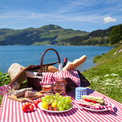 A picture of a picnic (basket, drinks & food) in a beautiful landscape