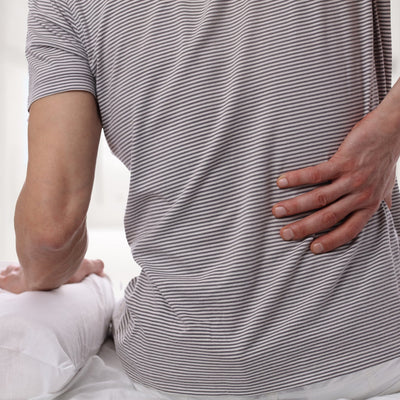 Man sat on bed holding back