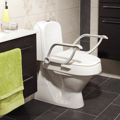 Raised toilet seat with arms in bathroom