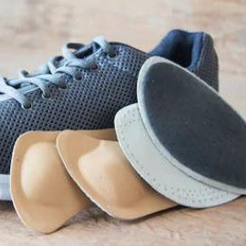 the image shows four insoles next to a trainer