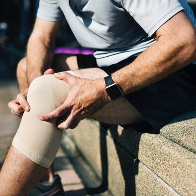 the image shows a man sat on a wall with a leg/knee protector on
